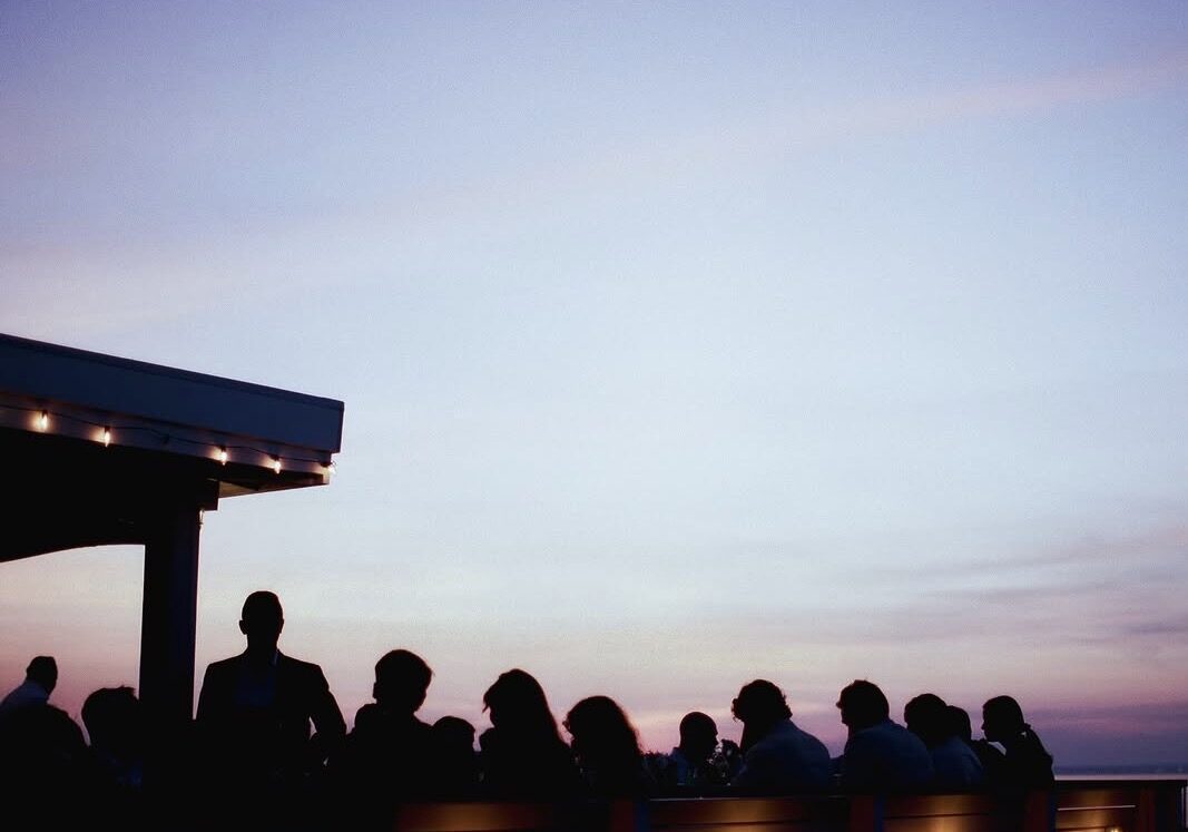 Silhouetted guests on the deck at dusk